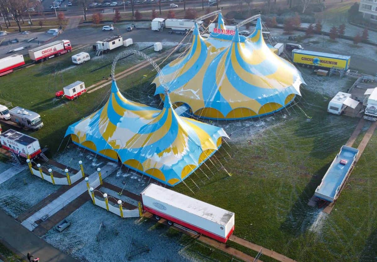 Circustent van boven gezien, met vrachtwagens en woonwagens eromheen