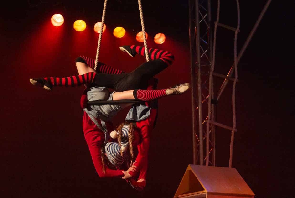 Twee trapeze-artiesten hangen ondersteboven in de nok van de tent